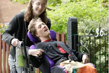 Personal assistant pushing disabled person in a wheelchair