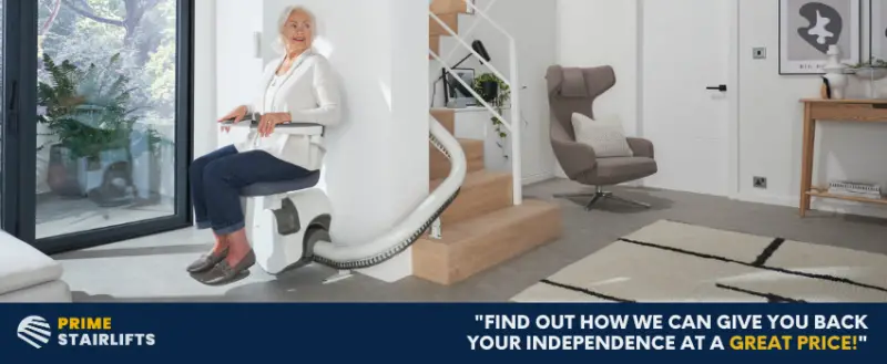 An older woman sat on a stairlift at the bottom of a curved staircase in a modern hallway