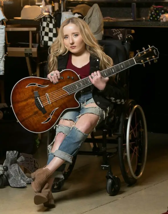 Disabled musician Ali McManus in her wheelchair holding a guitar