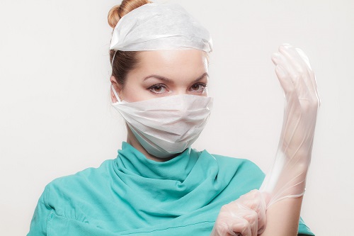 Nurse with gown, face mask, hair net and rubber gloves on