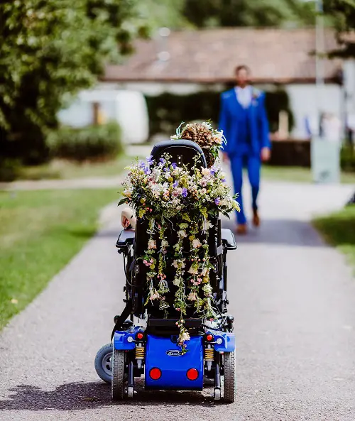 Tori's wheelchair from behind covered in flowers on her wedding day