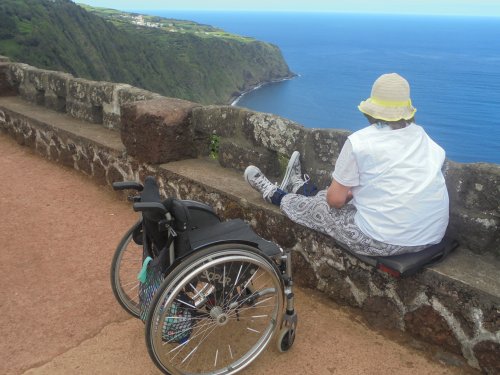 Wheelchair user sat on wall looking over lake in Azores