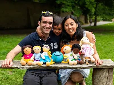 Rafael Tselikas, son Alex and Winnie Mak smiling at camera holding six disability dolls