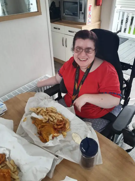 Emma sat at the table in accessible caravan eating fish & chips