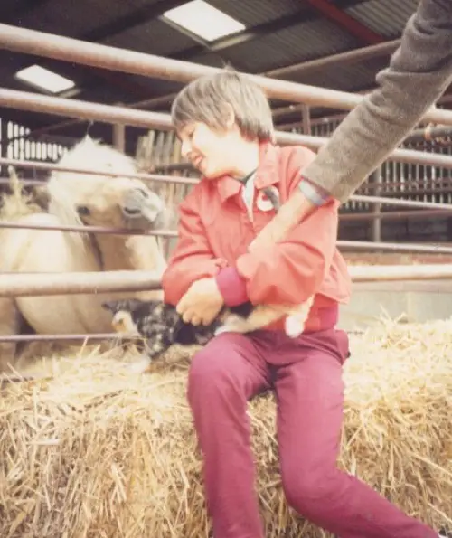 Disabled activist Simon Stevens as a child sat on a hay bail at a farm