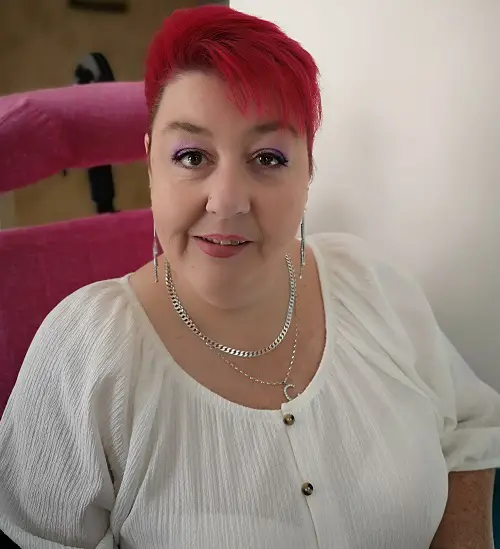 Caroline in her wheelchair with pink hair and headrest