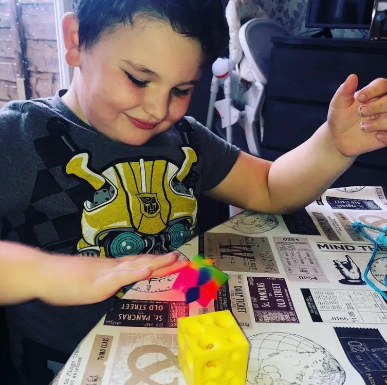 Leo sat at a table playing with sensory toy for people with autism