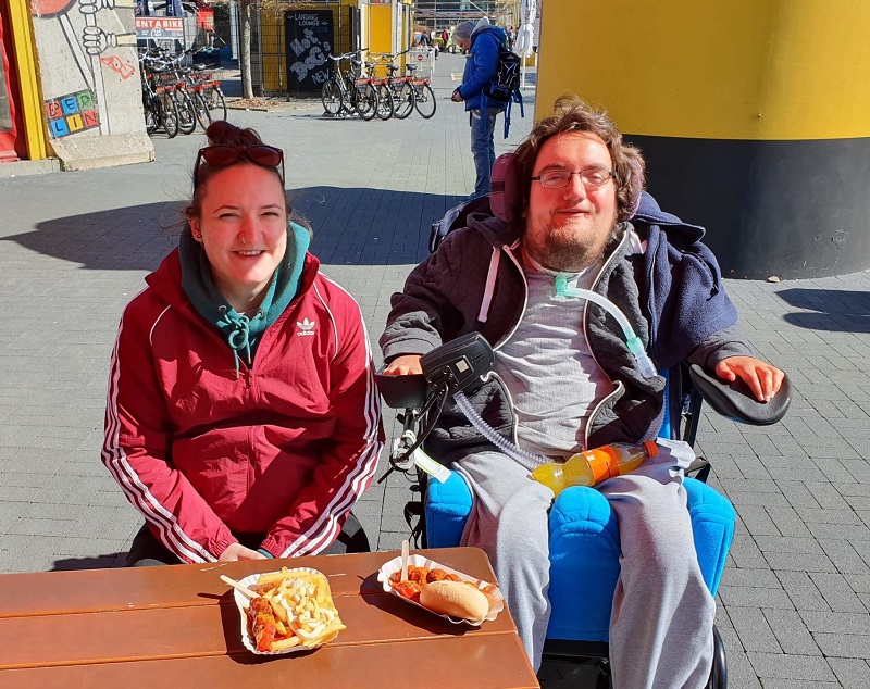 Derry Felton in his wheelchair at a cafe in Berlin having a Frankfurter