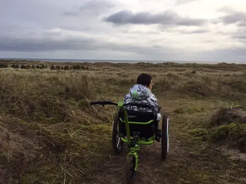 Andrew in the MT Push all-terrain wheelchair in a field with rough grasses