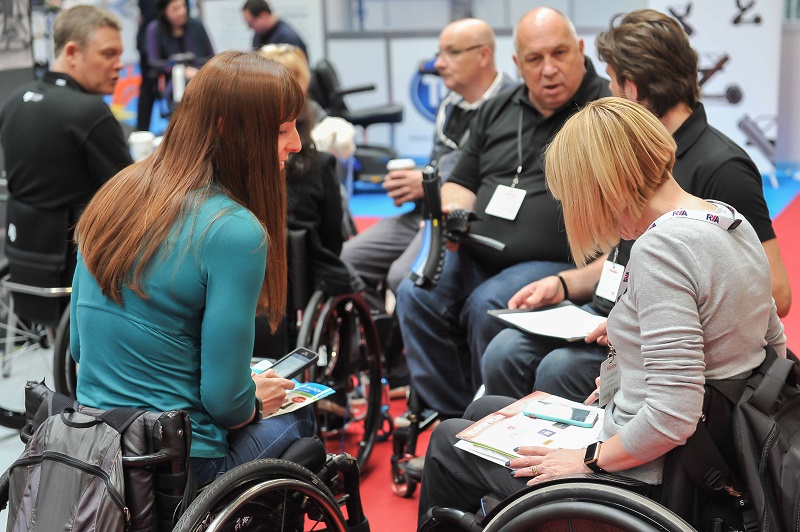 Men and women in wheelchairs talking at Naidex