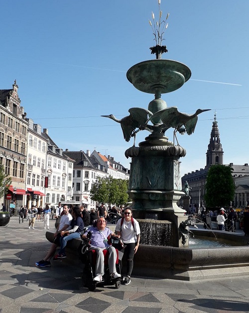 Wheelchair user Derry with his PA in front of a fountain in Copenhagen