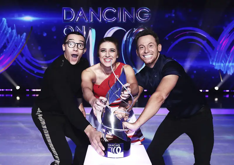 Dancing on Ice finalists Libby Clegg, Perri Kiely and Joe Swash on the ice rink holding the trophy