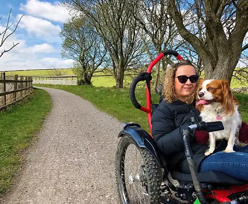 Carrie-Ann in her all-terrain wheelchair on a walk with her dog