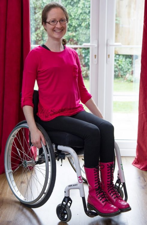 Hannah Ensor from Stickman Communications in her wheelchair in a pink top and boots with black trousers