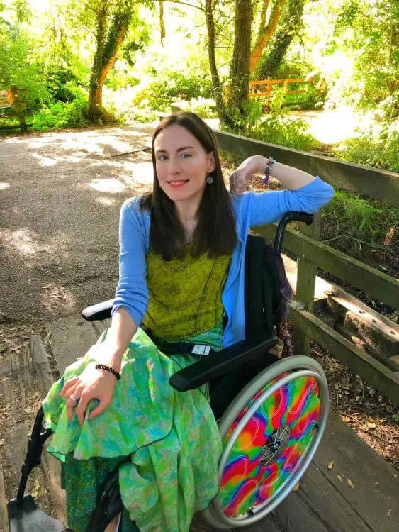 Rebecca posing in her wheelchair outside.