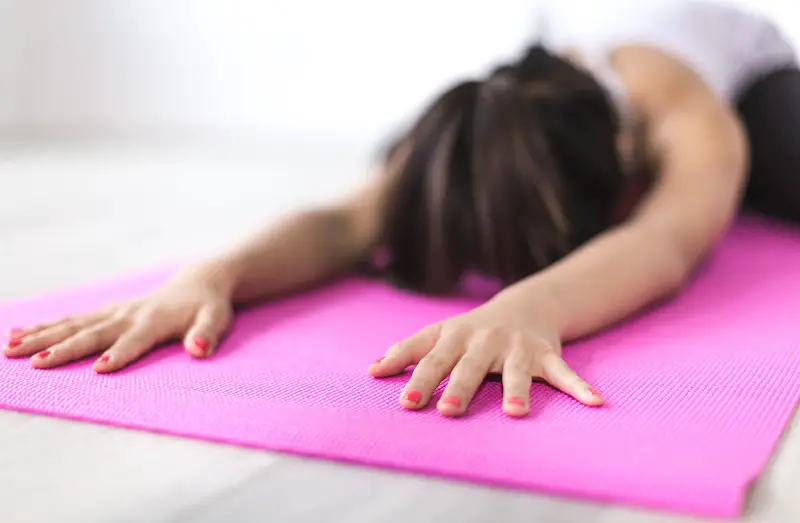 Woman laying on a pilates mat bending forward stretching