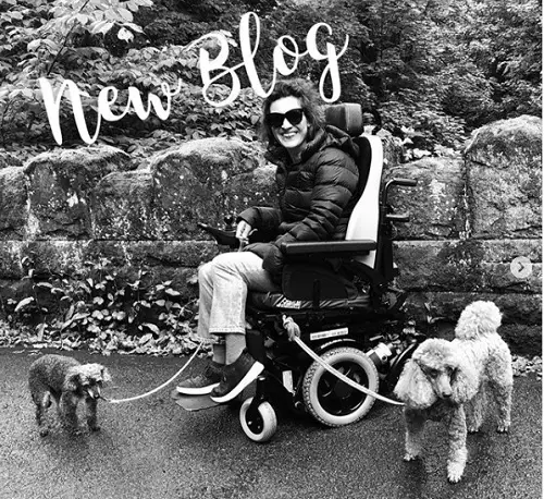 Black and white image of Lucy Reynolds in her wheelchair with her two dogs and the words new blog across the top