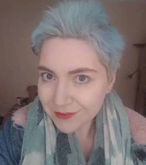 Close up of Daisy Holder with short pale blue hair, blue scarf and denim jacket