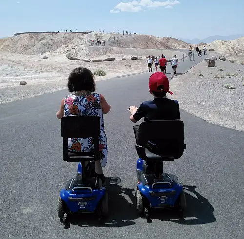 Emma and her son Archie on mobility scooters facing away from the camera in front of a dessert