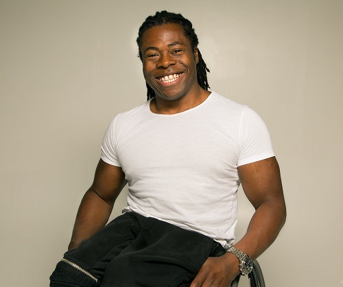 Ade Adepitan sat in his wheelchair in a white t-shirt with a basket ball on his lap
