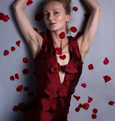 Blind fashion designer Nicole Hind wearing a red dress from her collection lying on the floor surrounded by red petals