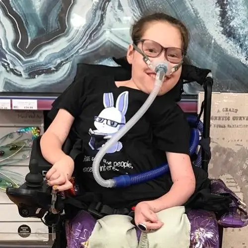 Fleur Perry in her wheelchair with her ventilator on wearing a black T-shirt with a white rabbit on the front