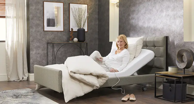 Woman sat in an adjustable bed with the back slightly raised
