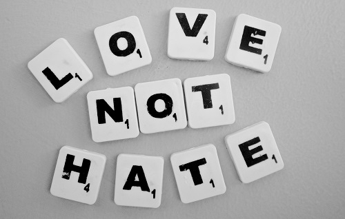 Words love not hate spelt out in scrabble letters on a white table