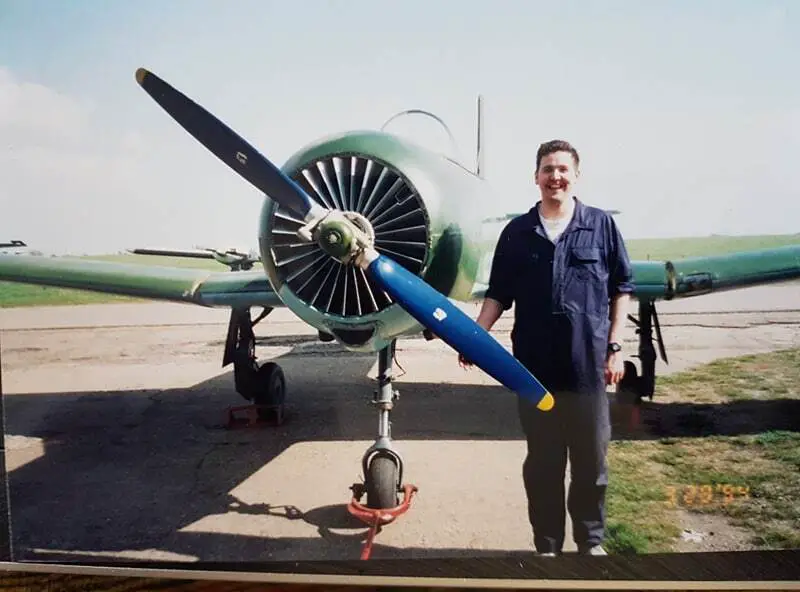 Darren in overalls standing next to green Airplane