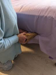 Lady using a bed wedge to tuck in sheets