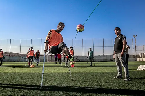 A man, who is an amputee and uses crutches, is playing football - Photo by Anas Aldyab from Pexels