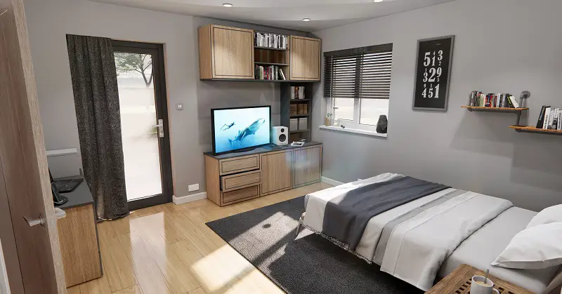 Accessible bedroom in an adapted modular home extension with lots of floor space, wooden flooring, a double bed and storage cabinets on the floor and wall