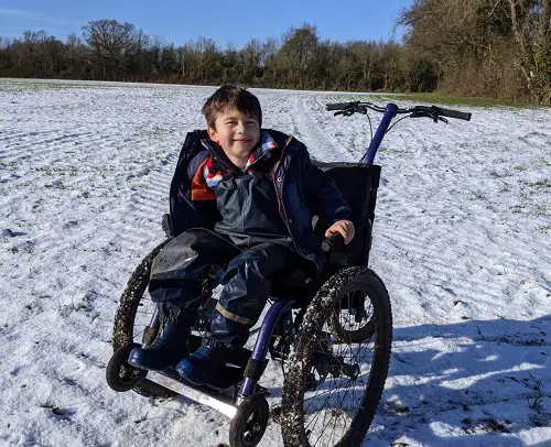 Archie in his Mountain Trike all-terrain wheelchair in a snow-covered field