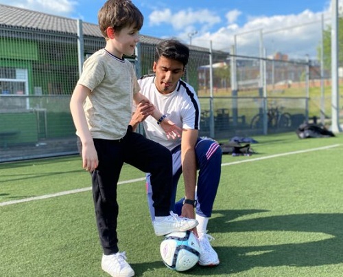 Visually impaired footballer Azeem showing a young boy to play football