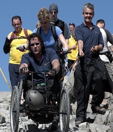 Grant Logan travelling to Ben Nevis to raise money for Capability Scotland.The Photo shows Grant in an terrain manual wheelchair climbing Ben Nevis. Grant is wearing black ttrousers and a blue T-shirt with sunglasses on his face.