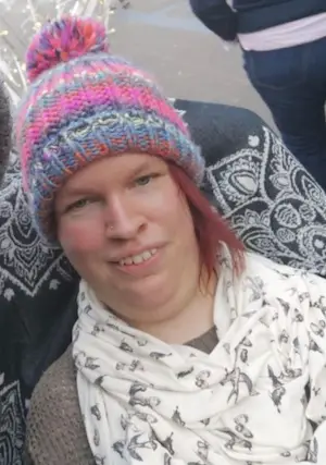 Gemma wearing a knitted rainbow hat and cream scarf with small birds printed on