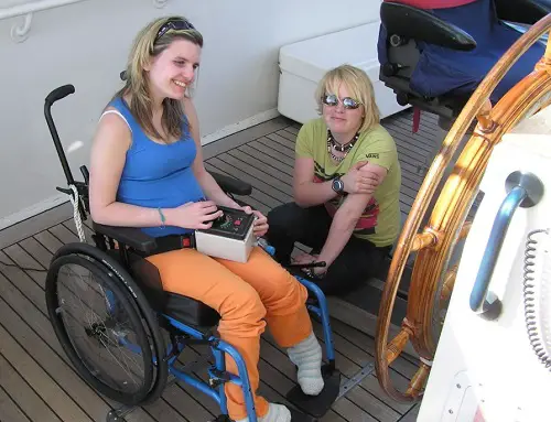 A young woman in a wheelchair using a joystick to sail the Jubilee Sailing Trust's fully-accessible ship