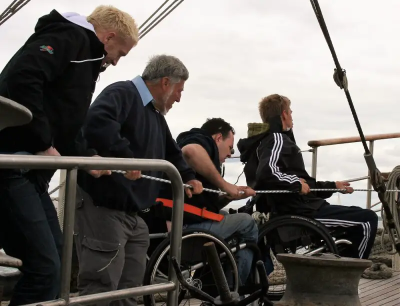 Four people, including two wheelchair users, pulling the ropes together on Jubilee Sailing Trust's fully-accessible ship