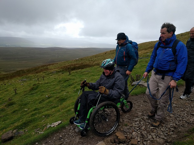 A man in an all-terrain wheelchair from Mountain Trike going down a rocky mountain
