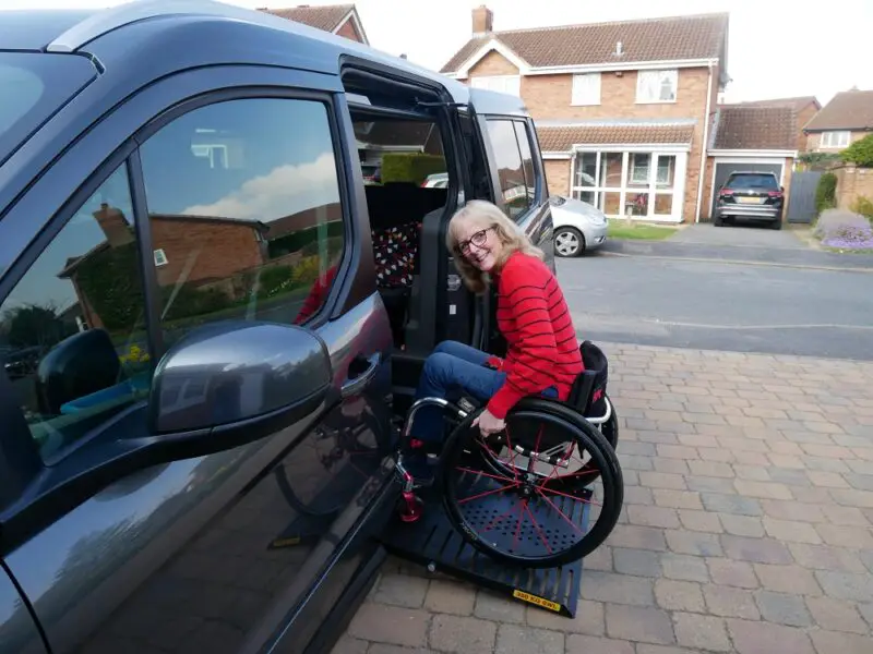 Wheelchair user Susan wearing a red and black top getting into her Sirus Ford Grand Tourneo Connect wheelchair accessible vehicle with internal transfer