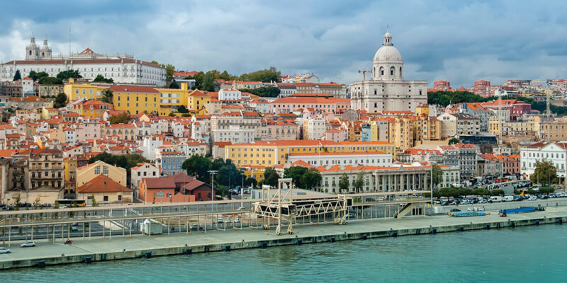 A marina by river Tagus in Lisbon by old town Alfama with white and bright yellow and orange buildings