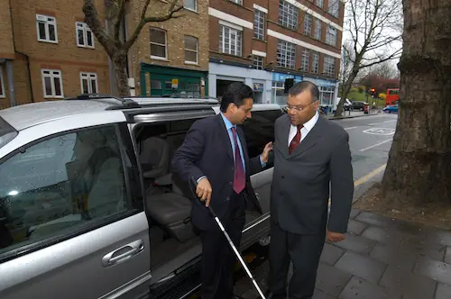 Partially sighted man wiht cane getting out of a PHV.